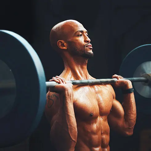 A Muscular Man Performing A Barbell Overhead Press, Demonstrating Strength And Focus In A Gym Setting, Highlighting The Muscle Gain Process.