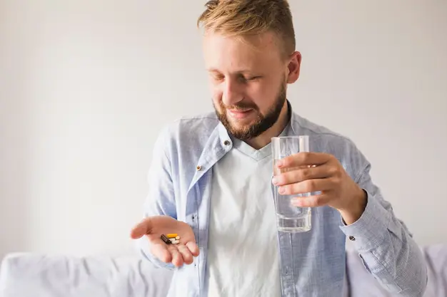 Man Taking The T3 Cytomel Pills And Drinking Water